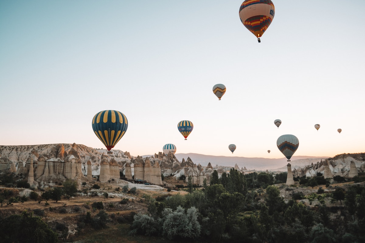 Colourful hot air balloons rising over the fairy chimneys of Cappadocia at sunrise — solo travel in Türkiye